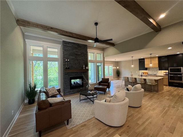 living room with a multi sided fireplace, baseboards, beam ceiling, and light wood finished floors