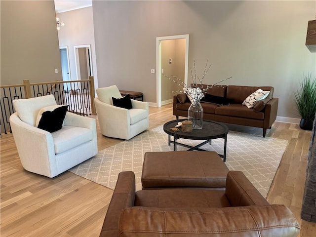 living area featuring baseboards, wood finished floors, and a towering ceiling