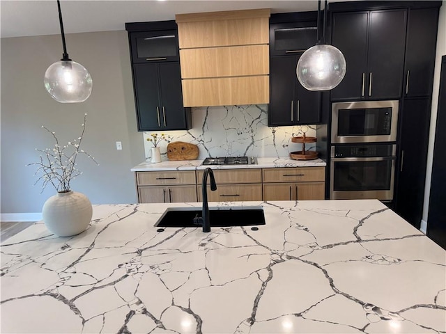 kitchen featuring appliances with stainless steel finishes, tasteful backsplash, a sink, light stone counters, and dark cabinets