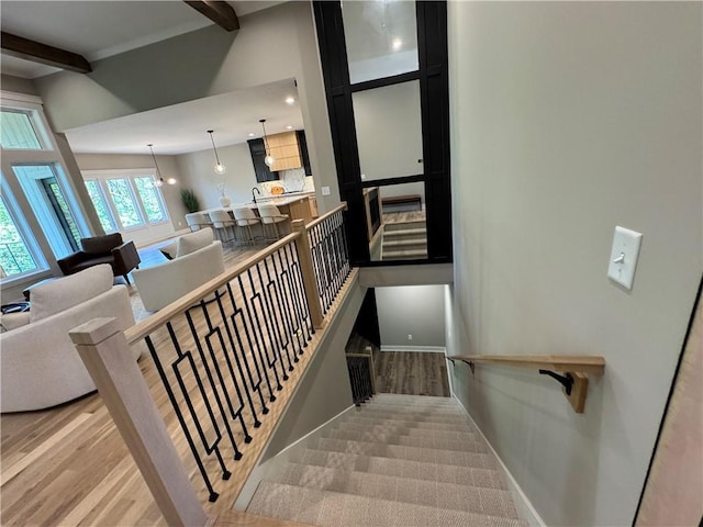 staircase with recessed lighting, baseboards, beam ceiling, and wood finished floors
