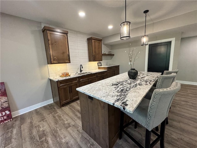kitchen with dark wood-style flooring, baseboards, decorative backsplash, and a sink