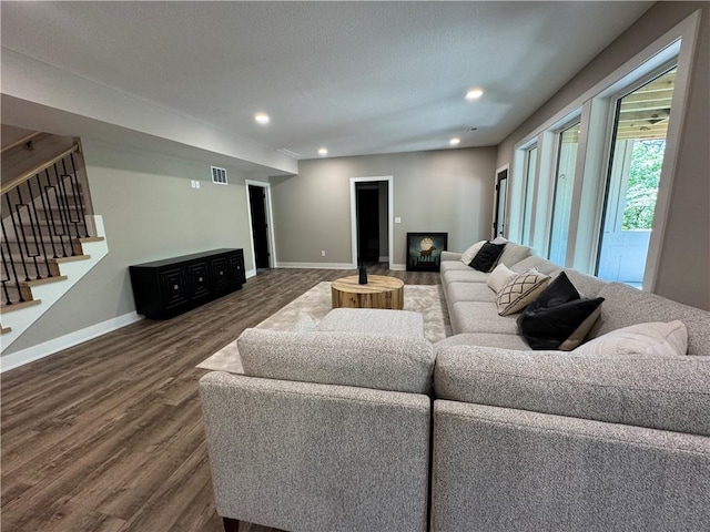 living room featuring visible vents, stairs, wood finished floors, baseboards, and recessed lighting