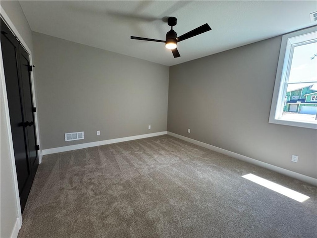 carpeted spare room with baseboards, a ceiling fan, and visible vents
