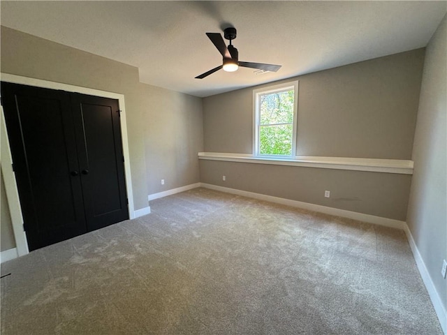 unfurnished bedroom featuring a closet, baseboards, a ceiling fan, and light colored carpet