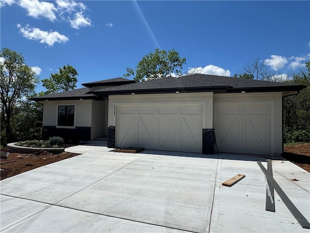 prairie-style home with a garage, stucco siding, and driveway