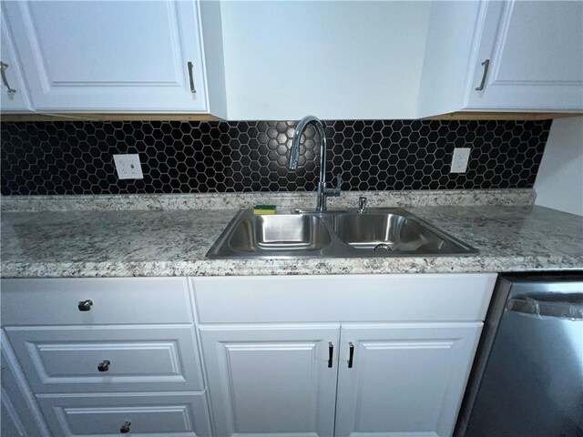 kitchen featuring tasteful backsplash, white cabinets, dishwasher, and a sink