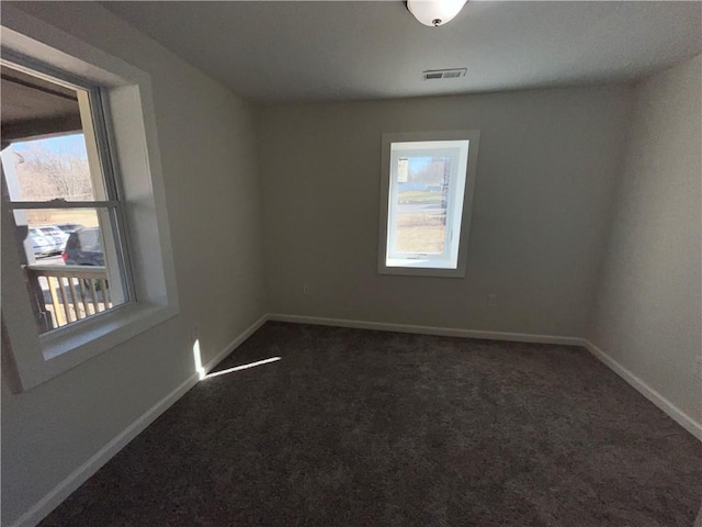 unfurnished room with visible vents, baseboards, and dark colored carpet