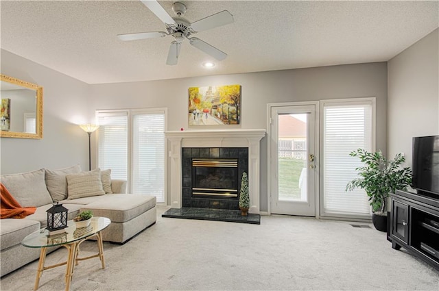 carpeted living area featuring visible vents, a tiled fireplace, a textured ceiling, recessed lighting, and ceiling fan