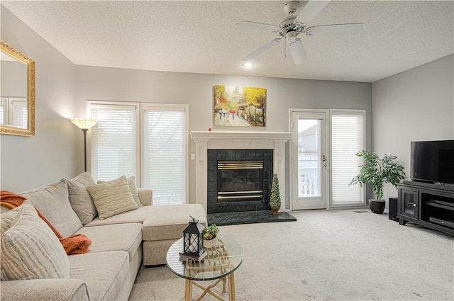 carpeted living area with a wealth of natural light, a textured ceiling, a ceiling fan, and a tile fireplace