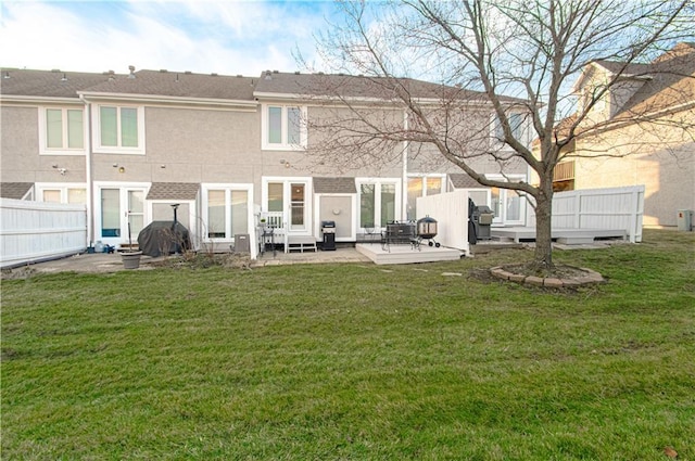 rear view of property featuring a patio area, a yard, and fence