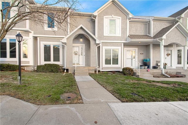 townhome / multi-family property with stucco siding and a front yard