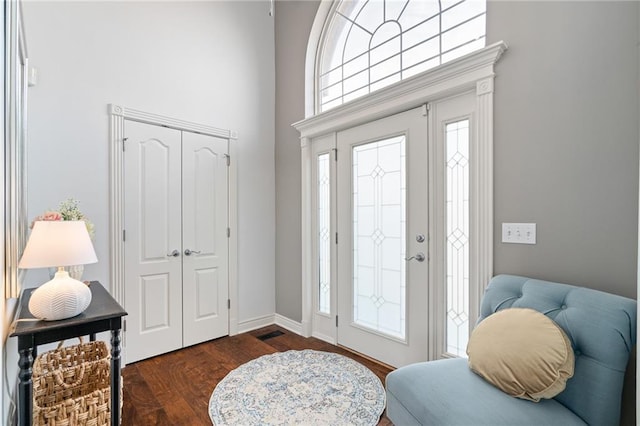 entryway featuring baseboards, dark wood-type flooring, and a high ceiling