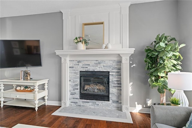 living area with a fireplace, baseboards, and wood finished floors