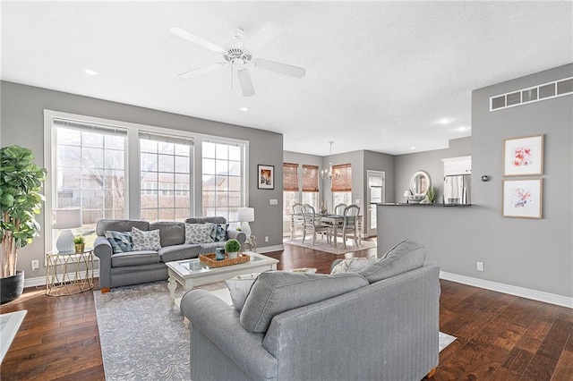 living room with visible vents, dark wood-type flooring, baseboards, recessed lighting, and ceiling fan with notable chandelier