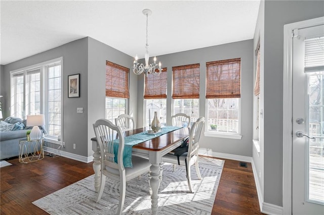 dining area featuring hardwood / wood-style floors, baseboards, and a chandelier