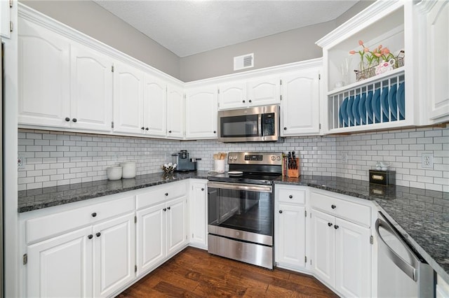 kitchen with visible vents, dark wood-style flooring, decorative backsplash, appliances with stainless steel finishes, and white cabinetry