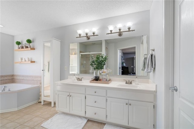 bathroom with double vanity, a stall shower, a sink, tile patterned flooring, and a textured ceiling