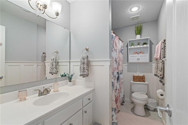 full bath with visible vents, a wainscoted wall, a textured ceiling, a decorative wall, and vanity