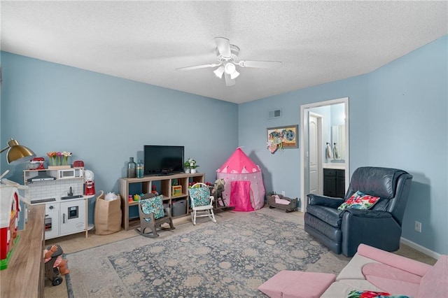 rec room with visible vents, a textured ceiling, carpet, baseboards, and ceiling fan