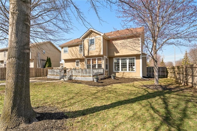 back of property featuring a yard, a wooden deck, and a fenced backyard