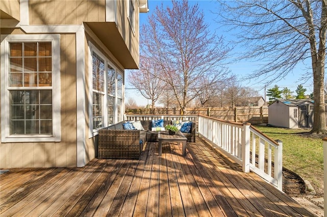 wooden terrace featuring an outbuilding, an outdoor living space, a storage unit, and a fenced backyard