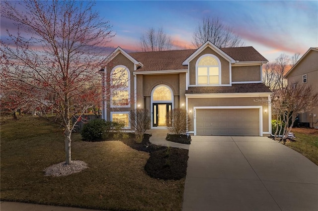 traditional-style house with stucco siding, driveway, a front lawn, and a garage