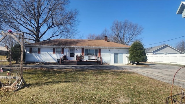 single story home featuring a chimney, a wooden deck, a front lawn, and fence