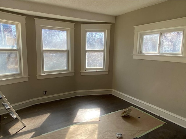 unfurnished room featuring a textured ceiling and baseboards