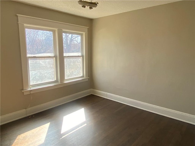 spare room featuring dark wood finished floors, baseboards, and a textured ceiling