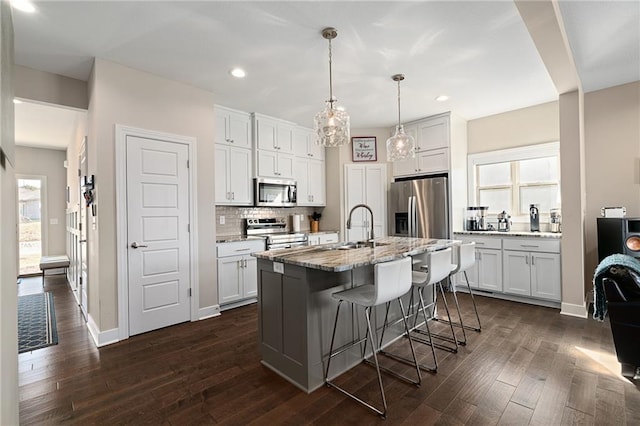 kitchen featuring stainless steel appliances, white cabinetry, a sink, and dark wood finished floors