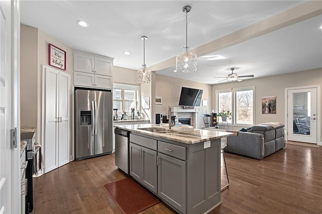 kitchen with a sink, dark wood-style flooring, appliances with stainless steel finishes, a fireplace, and gray cabinetry