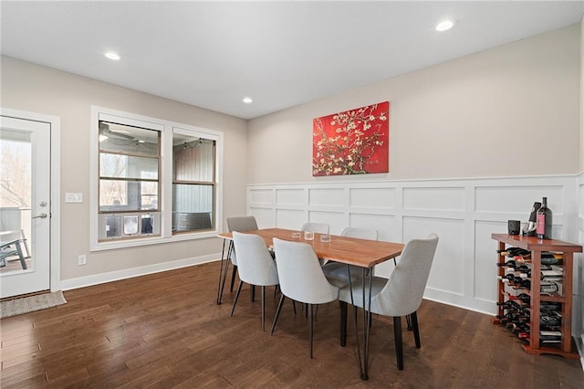 dining room with dark wood-type flooring, a decorative wall, and recessed lighting