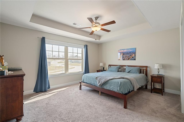 bedroom with a tray ceiling, baseboards, carpet, and visible vents