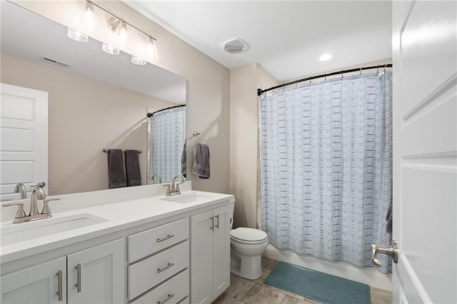 full bathroom with toilet, a sink, and visible vents