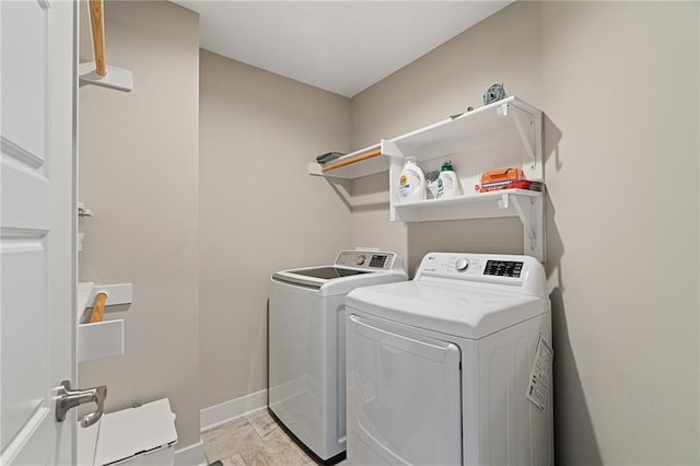 clothes washing area with baseboards, washer and dryer, and laundry area