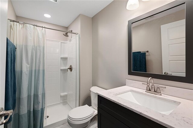 full bath with toilet, vanity, and a shower stall