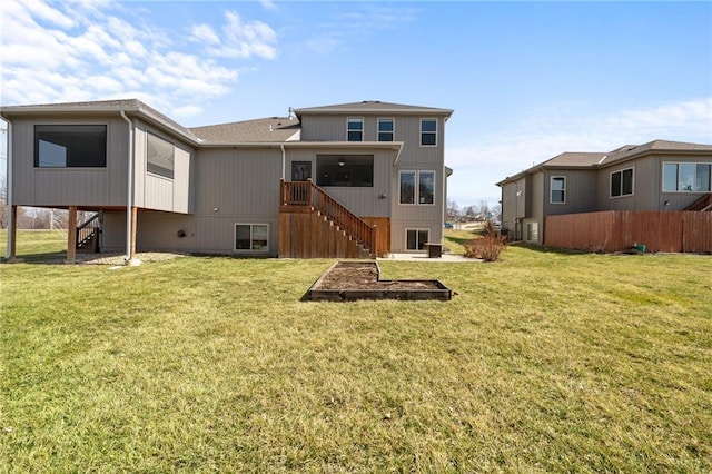 rear view of property with stairway and a lawn