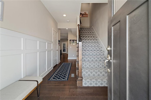entrance foyer featuring a decorative wall, dark wood-style flooring, stairway, recessed lighting, and wainscoting