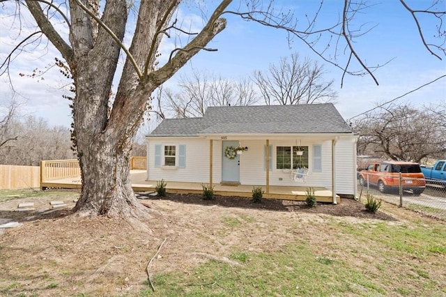 view of front of property with a porch, fence, and roof with shingles