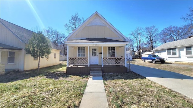 view of front of home featuring a front yard, covered porch, and a shingled roof