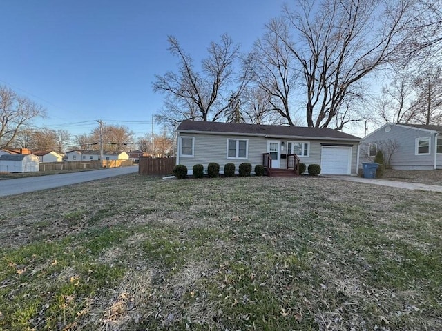 view of front of home featuring an attached garage, driveway, a front lawn, and fence