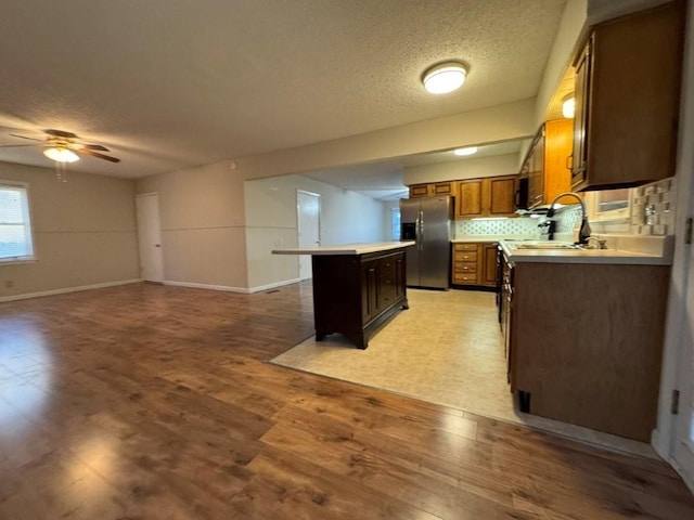 kitchen featuring light wood-type flooring, a kitchen island, open floor plan, stainless steel fridge with ice dispenser, and light countertops