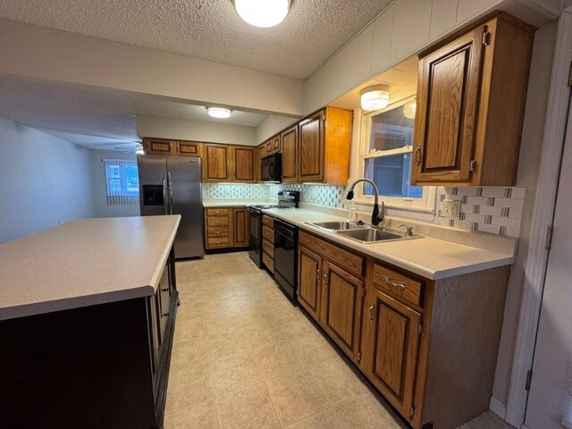 kitchen with black appliances, brown cabinetry, light countertops, and a sink