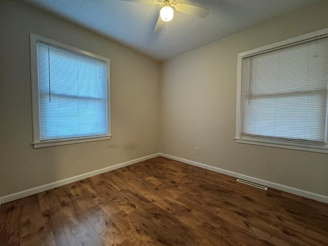 empty room with visible vents, ceiling fan, baseboards, and wood finished floors