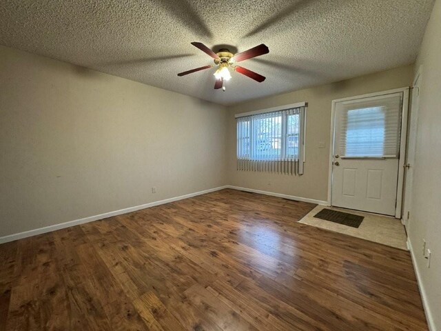 interior space with a ceiling fan, wood finished floors, baseboards, and a textured ceiling