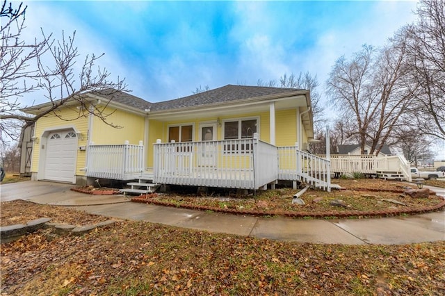 view of front of property featuring covered porch, an attached garage, concrete driveway, and roof with shingles