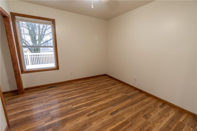 empty room featuring visible vents, baseboards, and wood finished floors