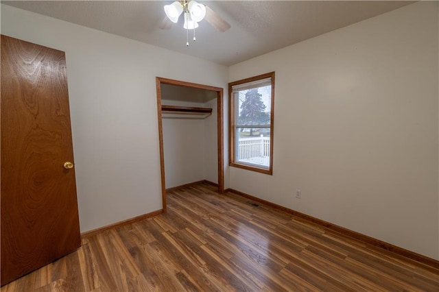 unfurnished bedroom with visible vents, a ceiling fan, wood finished floors, a closet, and baseboards