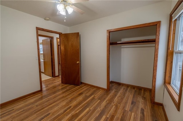 unfurnished bedroom featuring a closet, baseboards, wood finished floors, and a ceiling fan