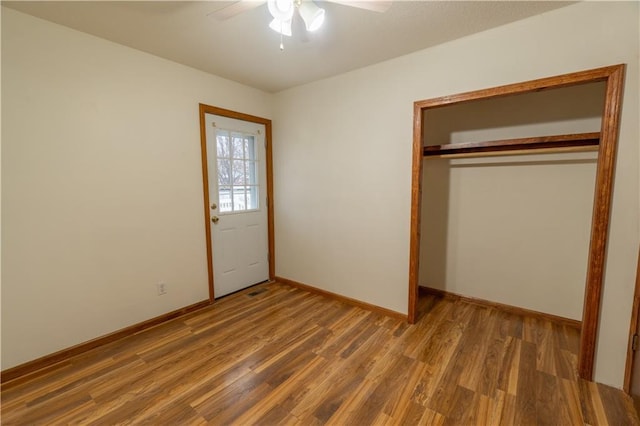 unfurnished bedroom with ceiling fan, a closet, baseboards, and wood finished floors